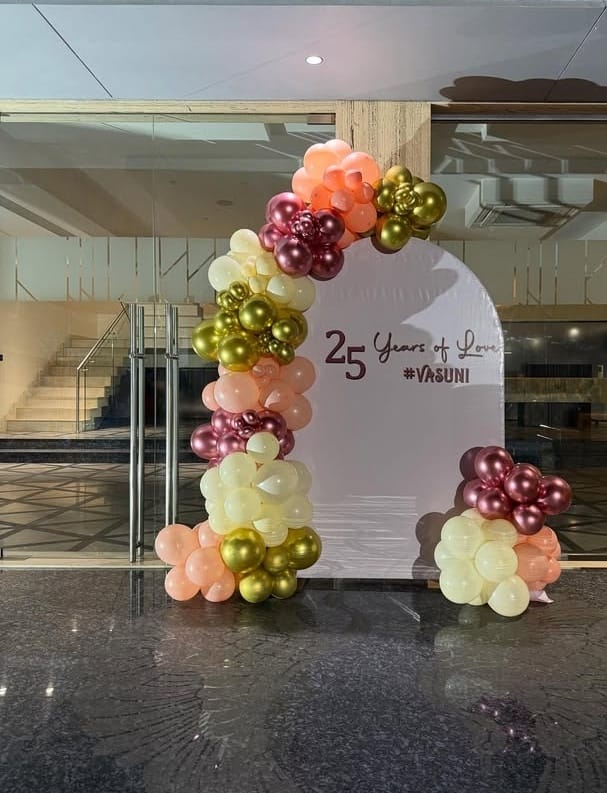 Chic 25th anniversary photo backdrop in Jaipur with peach, rose gold, and metallic gold balloons by Shava Moments.
