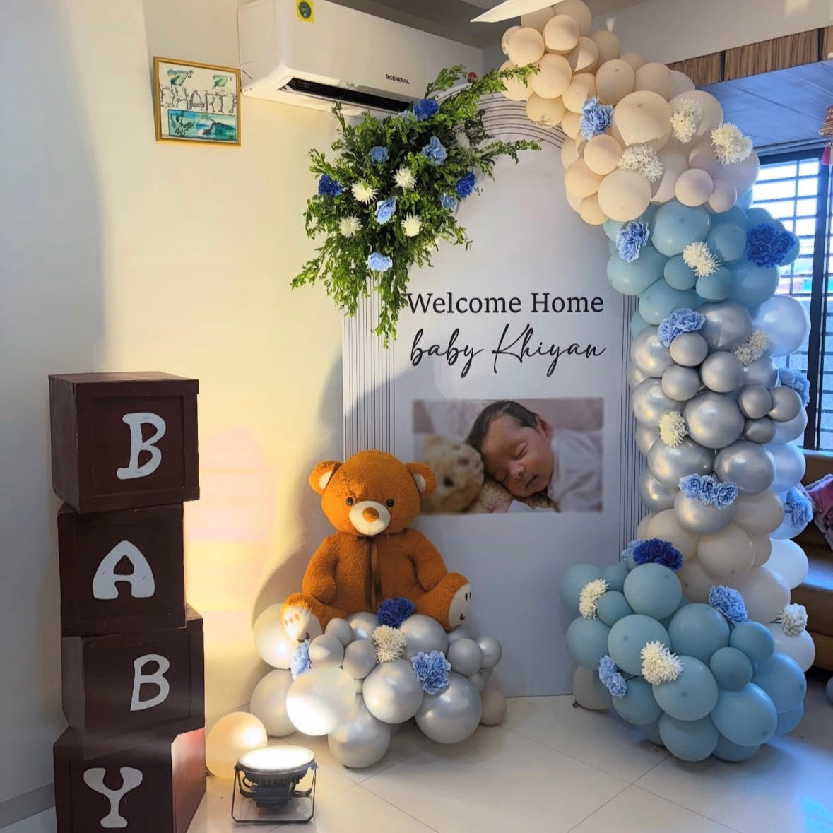 Luxury baby boy welcome decoration in Jaipur with a personalized photo backdrop, giant plush teddy bear, and blue and silver chrome balloons by Shava Moments.