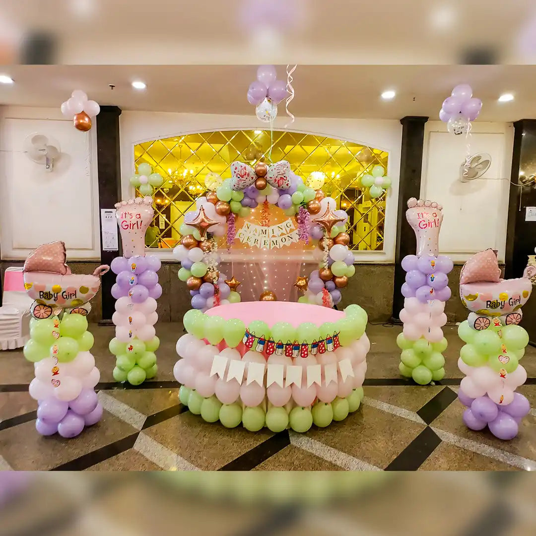 Symmetrical naming ceremony decoration for a baby girl in Jaipur featuring pastel rainbow balloons and baby stroller props by Shava Moments.