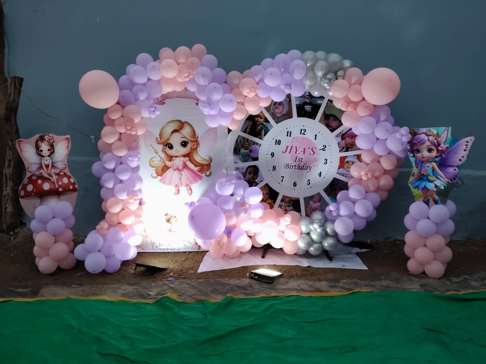 Personalized fairy-themed 1st birthday backdrop with a photo milestone clock and pastel balloons in Jaipur by Shava Moments.