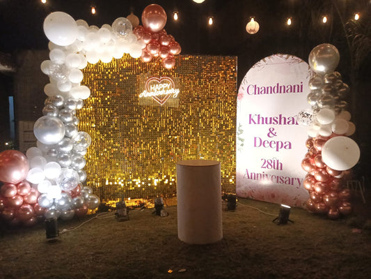 Evening outdoor anniversary decoration in Jaipur featuring a gold shimmer wall, neon sign, and metallic balloon arch by Shava Moments.