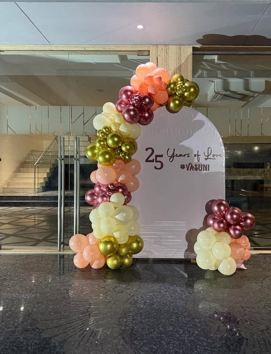Chic 25th anniversary photo backdrop in Jaipur with peach, rose gold, and metallic gold balloons by Shava Moments.