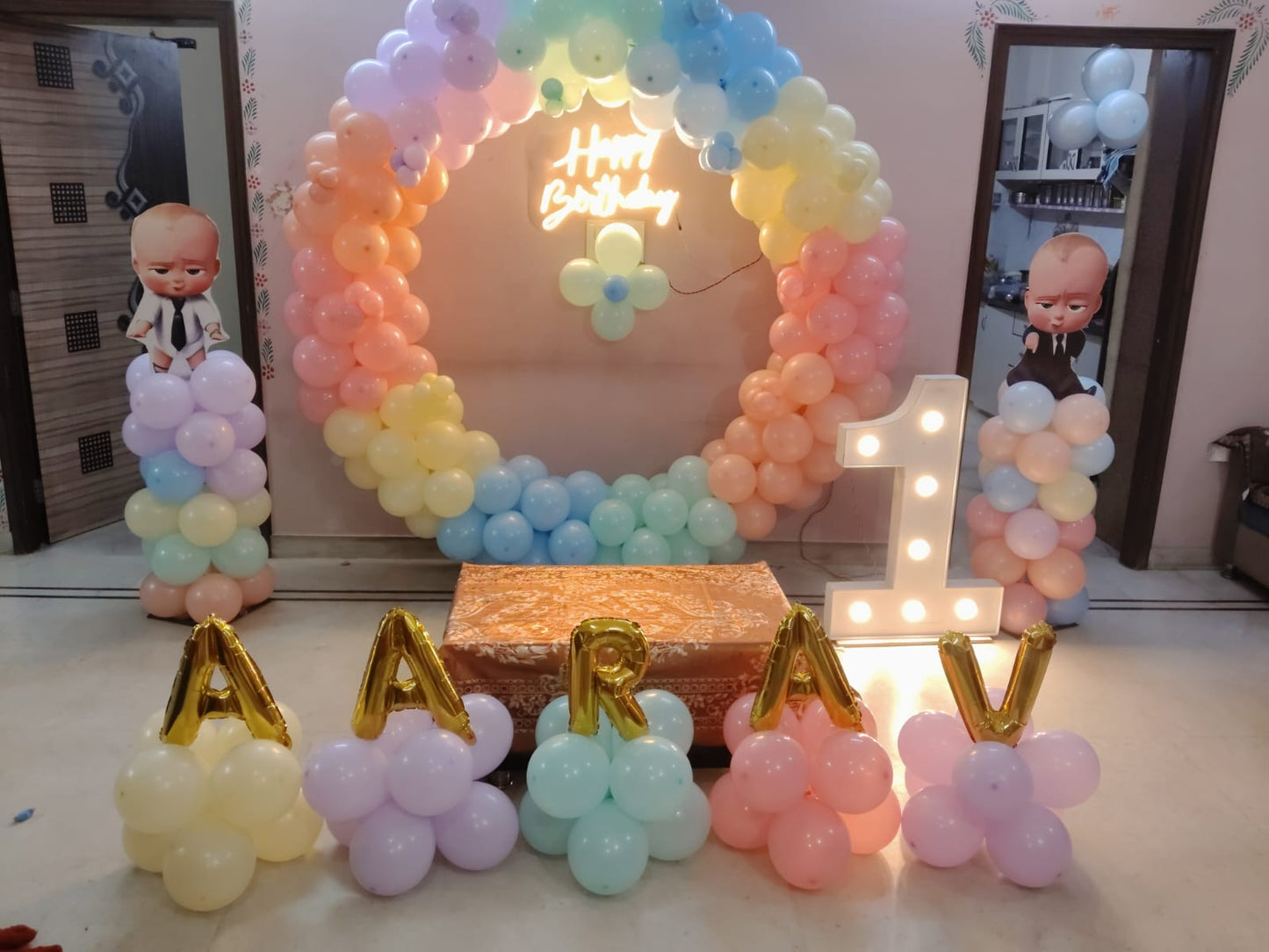 Colorful rainbow Boss Baby 1st birthday setup in a Jaipur home with a neon sign and gold letter balloons by Shava Moments.