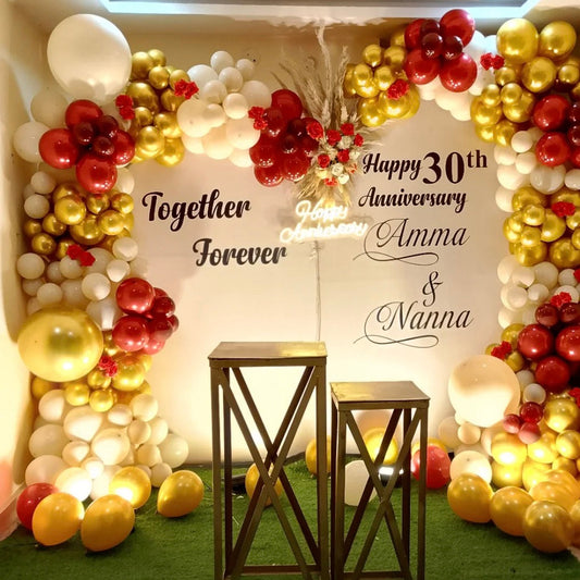 Warm white, crimson red, and gold balloon arch for a 30th anniversary celebration in Jaipur dedicated to parents by Shava Moments